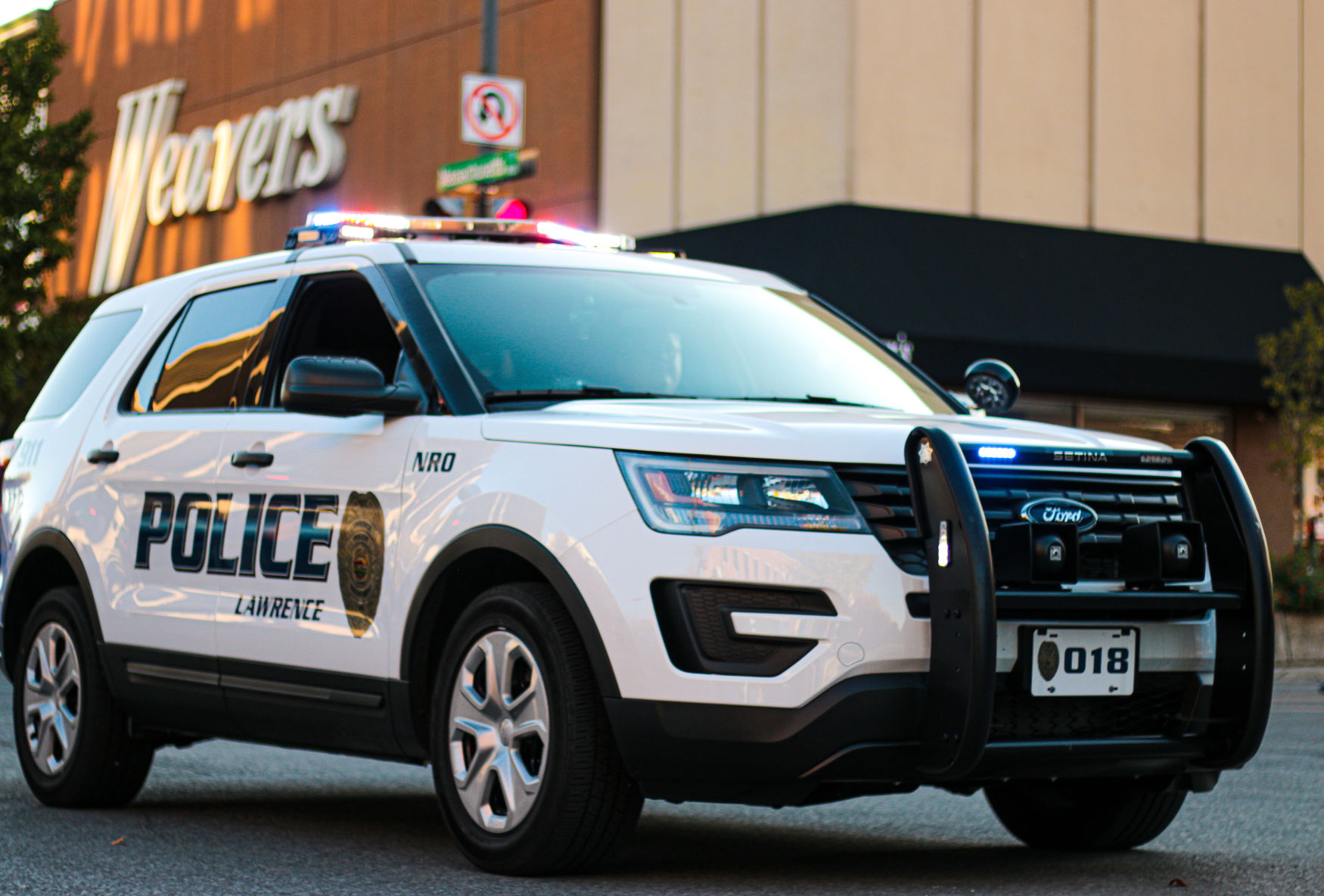 A Lawrence Police Department S.U.V. drives past Weavers Department Store on Massachusetts Street